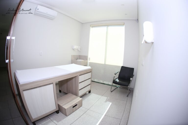 Consultório da Clínica Gattass Ferreira com maca de exame e mesa de atendimento