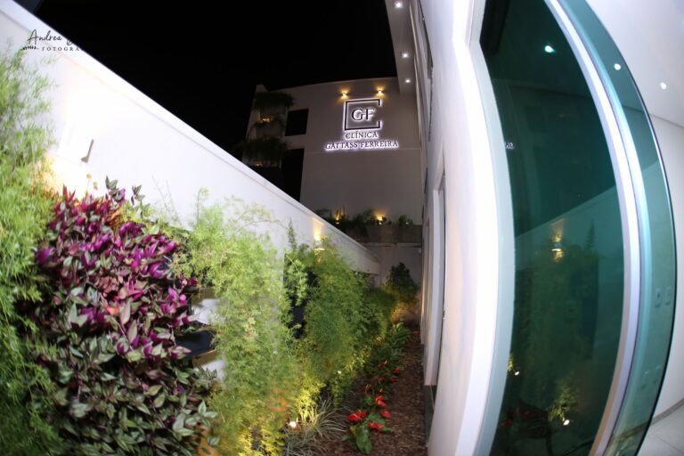 Fachada iluminada da Clínica Gattass Ferreira à noite, com jardim vertical