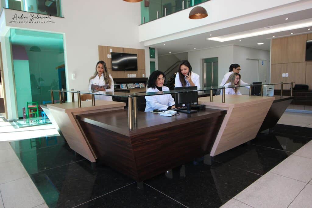 Equipe de atendimento no balc&atilde;o da recep&ccedil;&atilde;o da Cl&iacute;nica Gattass Ferreira